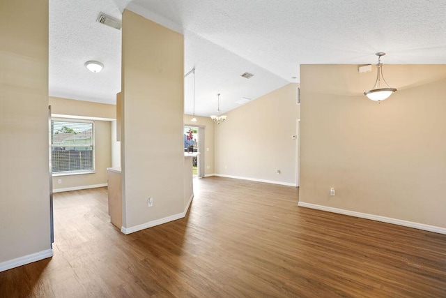 unfurnished living room with hardwood / wood-style floors, a textured ceiling, lofted ceiling, and a notable chandelier