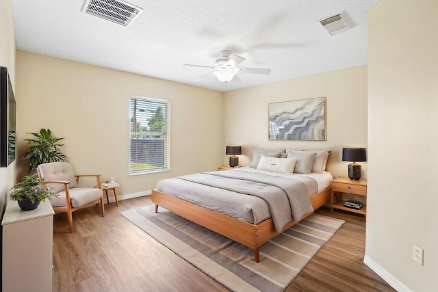 bedroom featuring ceiling fan, hardwood / wood-style floors, and a textured ceiling