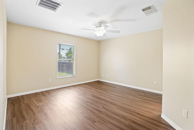 empty room featuring a textured ceiling, dark hardwood / wood-style floors, and ceiling fan