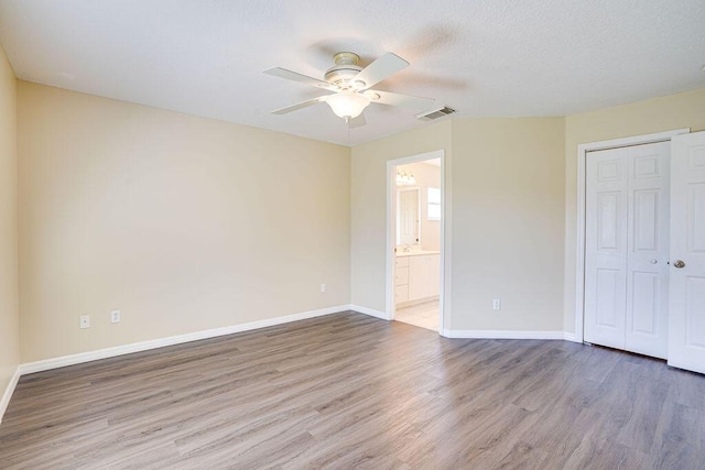 unfurnished bedroom featuring connected bathroom, ceiling fan, a closet, and hardwood / wood-style flooring