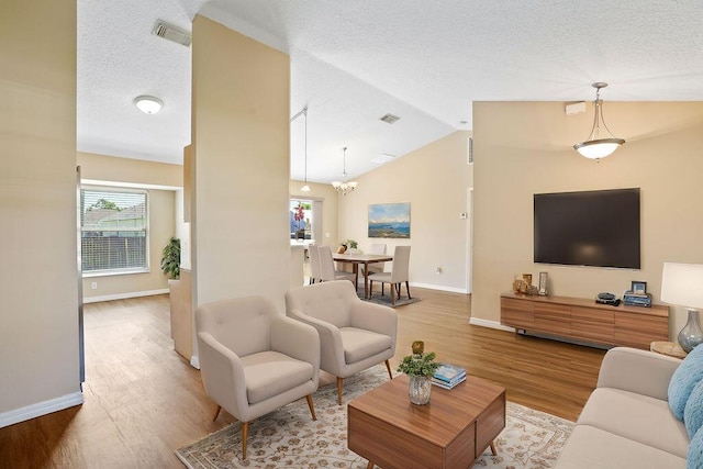 living room featuring a textured ceiling, a chandelier, vaulted ceiling, and hardwood / wood-style flooring