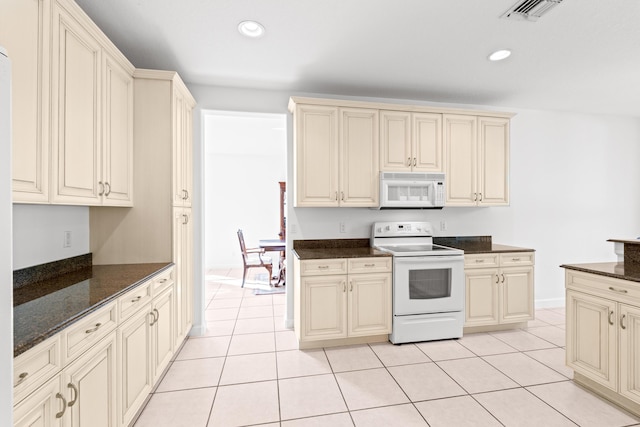 kitchen featuring cream cabinets, light tile patterned flooring, and white appliances