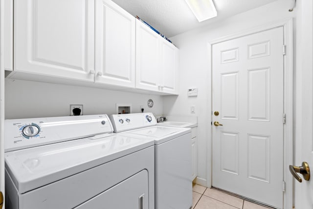 clothes washing area featuring cabinets, a textured ceiling, sink, separate washer and dryer, and light tile patterned flooring