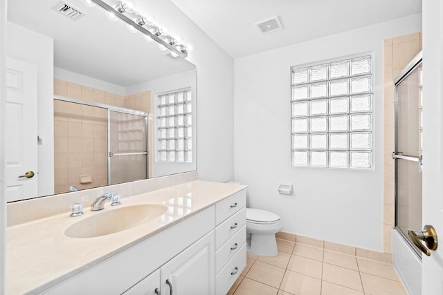 full bathroom with tile patterned floors, plenty of natural light, toilet, and bath / shower combo with glass door