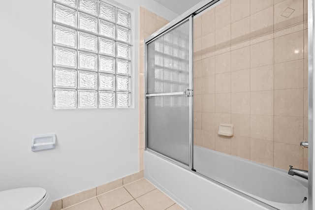 bathroom with tile patterned flooring, toilet, and bath / shower combo with glass door