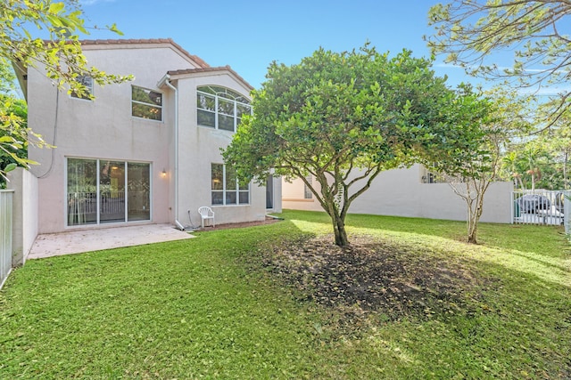 back of house featuring a lawn and a patio area