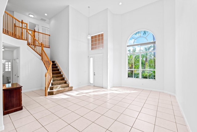 foyer entrance featuring a towering ceiling and light tile patterned floors