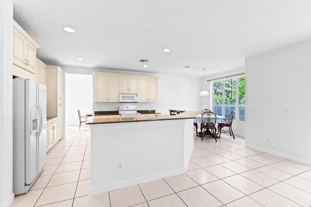 kitchen featuring decorative light fixtures, white appliances, light tile patterned floors, and cream cabinets