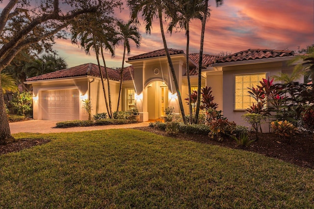 mediterranean / spanish-style home with a lawn and a garage