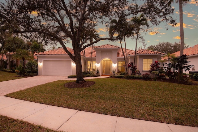 mediterranean / spanish-style home featuring a garage and a yard