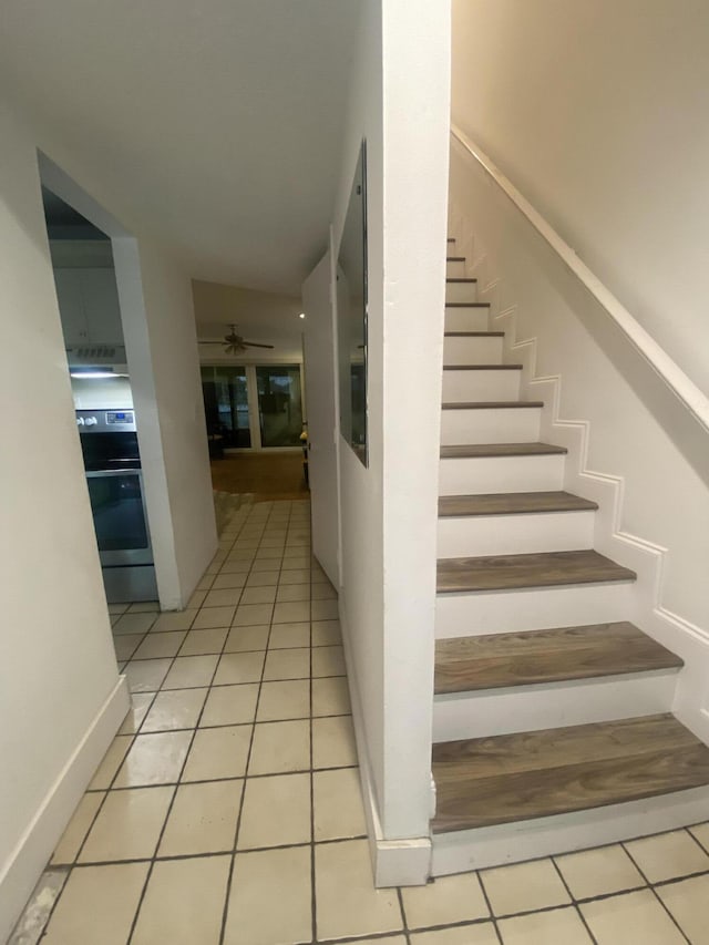 staircase featuring tile patterned flooring and ceiling fan