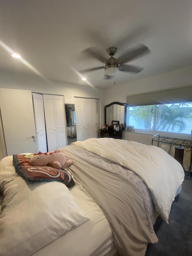 carpeted bedroom with ceiling fan and multiple closets