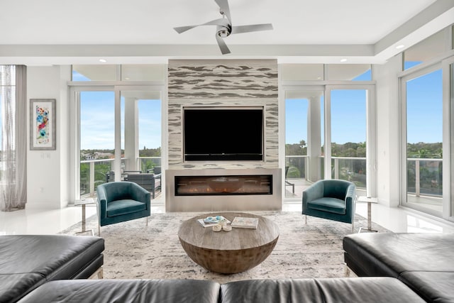 living room featuring a high end fireplace, a wealth of natural light, and ceiling fan