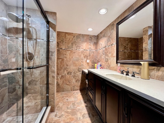 bathroom featuring a shower with door, vanity, and tile walls