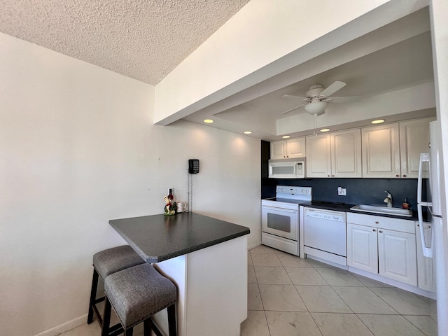 kitchen with white appliances, a kitchen breakfast bar, sink, kitchen peninsula, and white cabinetry