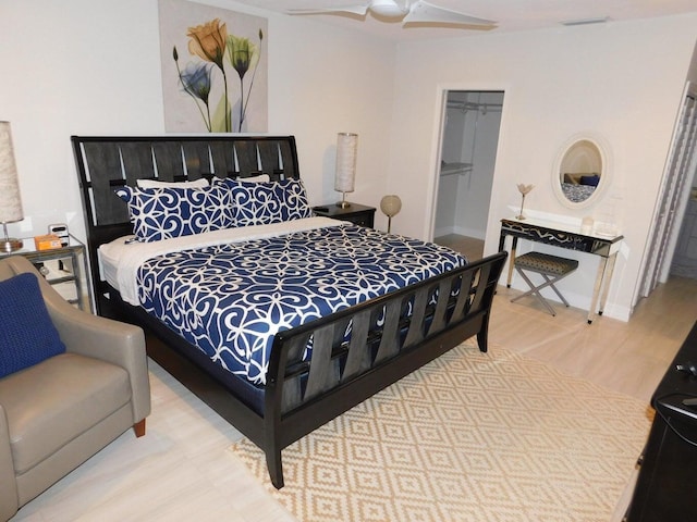 bedroom with ceiling fan, a walk in closet, light wood-type flooring, and a closet