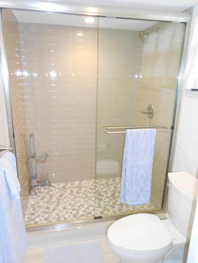 bathroom featuring tile patterned floors, toilet, and walk in shower