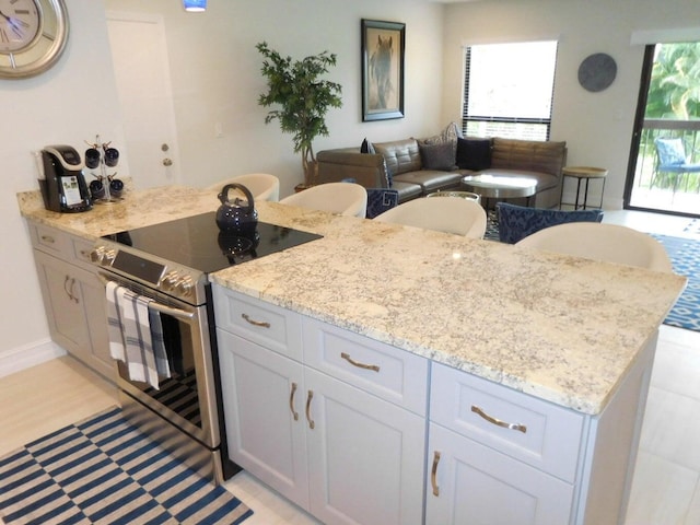 kitchen featuring white cabinets, stainless steel electric range oven, and light stone counters