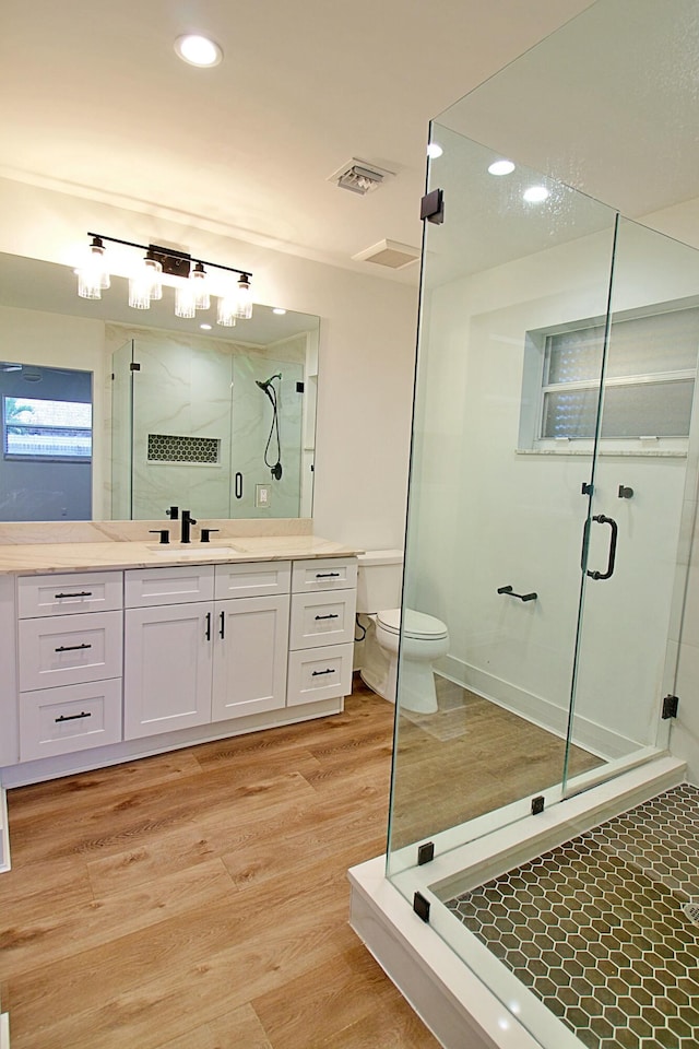 bathroom with hardwood / wood-style floors, vanity, toilet, and walk in shower