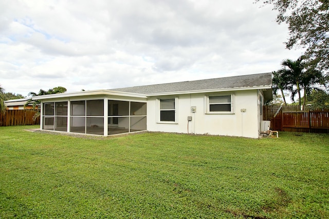 rear view of property featuring a lawn and a sunroom