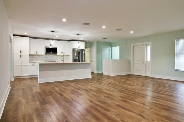 kitchen featuring pendant lighting, a kitchen island with sink, white cabinets, dark hardwood / wood-style floors, and stainless steel appliances