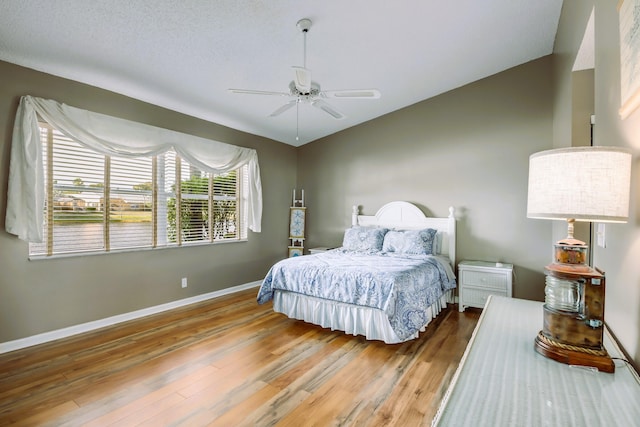 bedroom featuring ceiling fan, wood-type flooring, and a textured ceiling