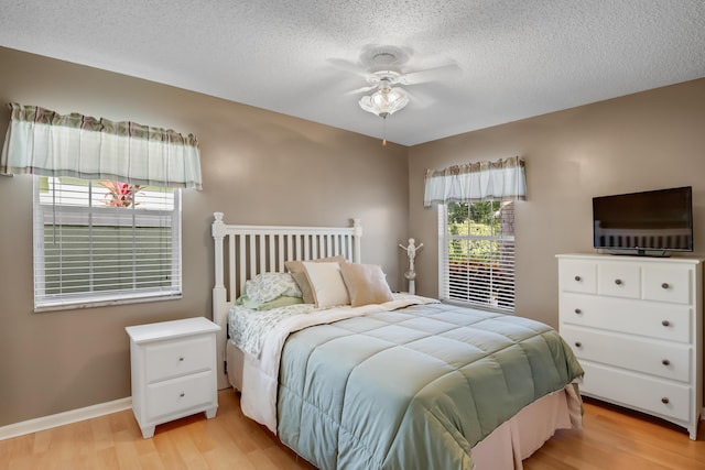 bedroom featuring ceiling fan, light hardwood / wood-style floors, and a textured ceiling