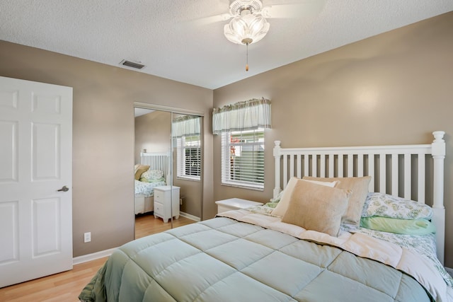 bedroom featuring ceiling fan, a closet, light hardwood / wood-style floors, and a textured ceiling