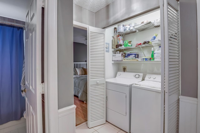 laundry room with light tile patterned flooring, independent washer and dryer, and a textured ceiling