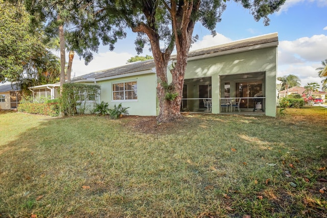 back of house featuring a lawn and a sunroom