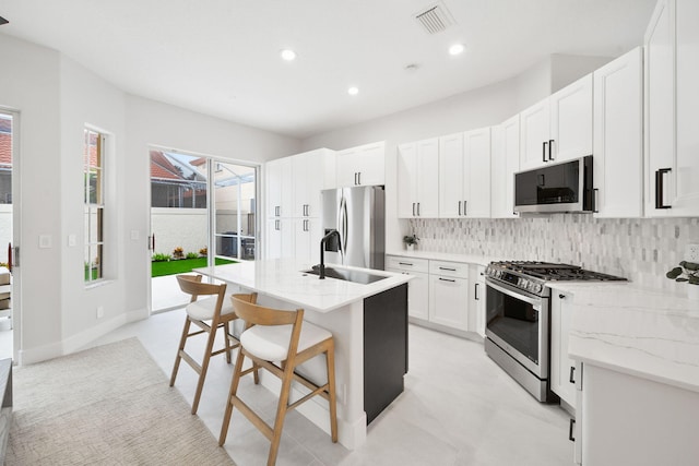 kitchen with white cabinetry, sink, a kitchen breakfast bar, an island with sink, and appliances with stainless steel finishes