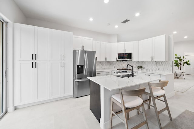 kitchen with light stone countertops, stainless steel appliances, white cabinetry, and sink