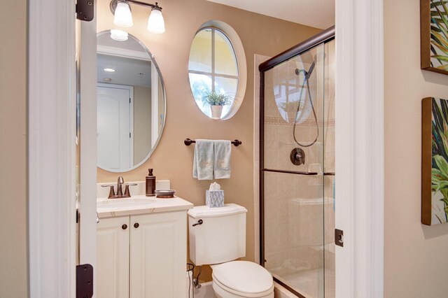 bathroom featuring walk in shower, vanity, and toilet