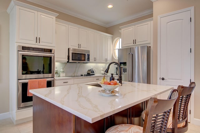 kitchen featuring light stone counters, white cabinetry, a kitchen island with sink, and appliances with stainless steel finishes