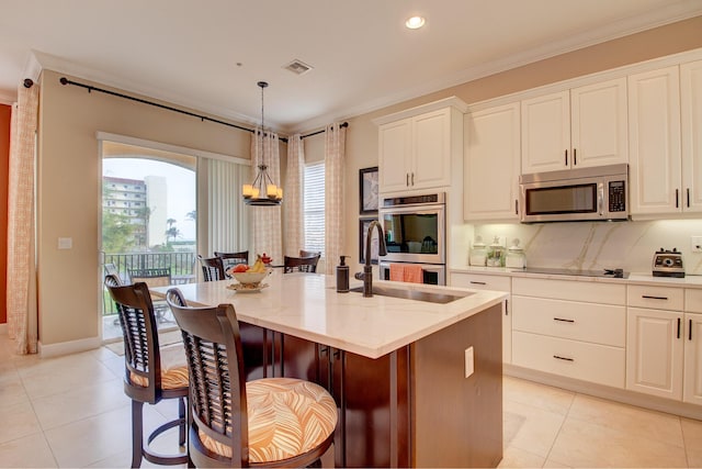 kitchen featuring white cabinetry, a center island with sink, hanging light fixtures, and appliances with stainless steel finishes