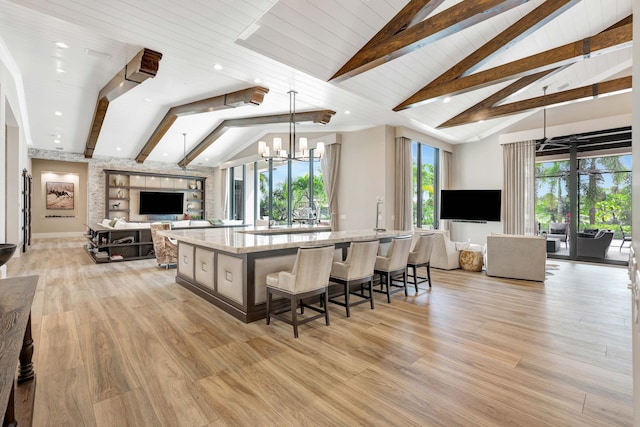 kitchen featuring light stone countertops, wooden ceiling, a large island with sink, light hardwood / wood-style floors, and decorative light fixtures