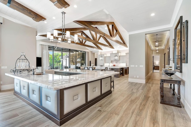 kitchen with light stone countertops, hanging light fixtures, and a spacious island