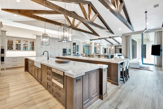 kitchen with decorative light fixtures, beam ceiling, and a spacious island