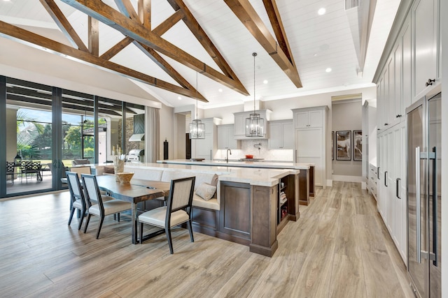 kitchen with backsplash, a spacious island, beam ceiling, decorative light fixtures, and high vaulted ceiling