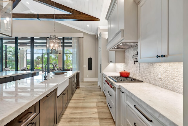 kitchen with light stone countertops, sink, lofted ceiling with beams, a notable chandelier, and backsplash