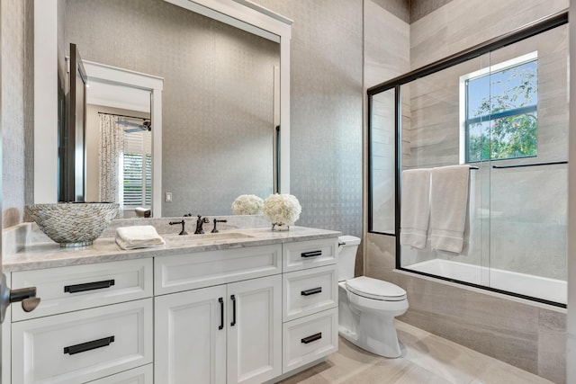 full bathroom with combined bath / shower with glass door, vanity, toilet, and ceiling fan