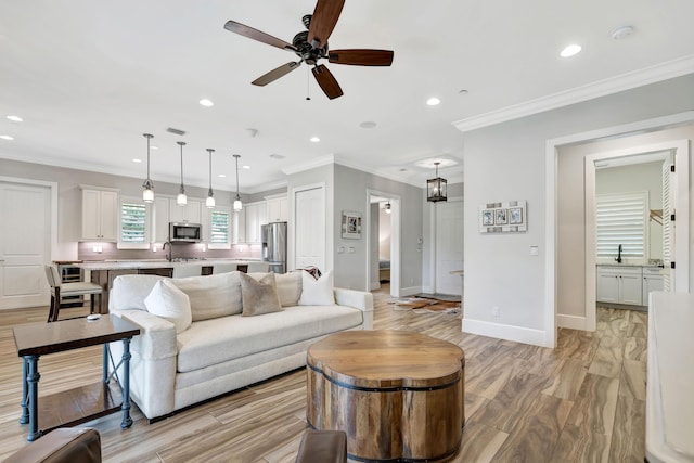 living room with ceiling fan, crown molding, and sink