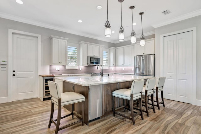 kitchen featuring white cabinets, a breakfast bar, stainless steel appliances, and a kitchen island with sink