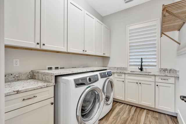 washroom featuring light hardwood / wood-style floors, sink, cabinets, and independent washer and dryer