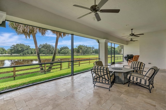 sunroom / solarium featuring ceiling fan and a water view