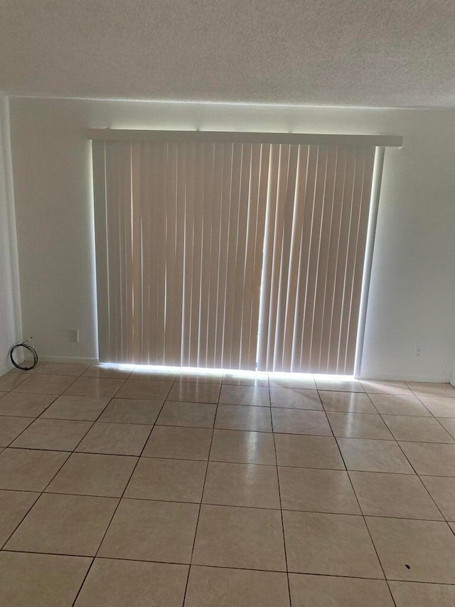 tiled spare room with a textured ceiling