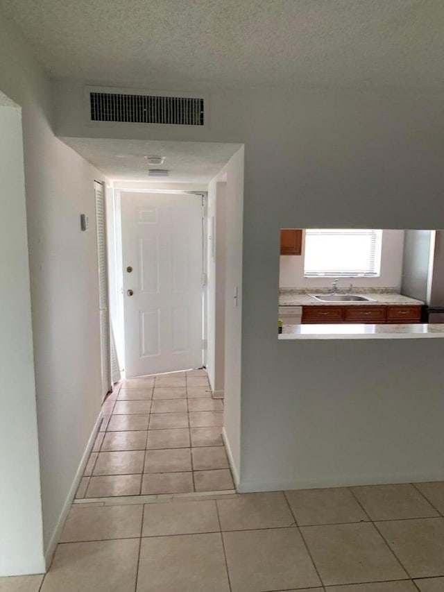 hall with sink, light tile patterned floors, and a textured ceiling