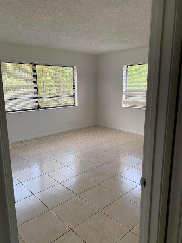 tiled empty room featuring a healthy amount of sunlight and a textured ceiling