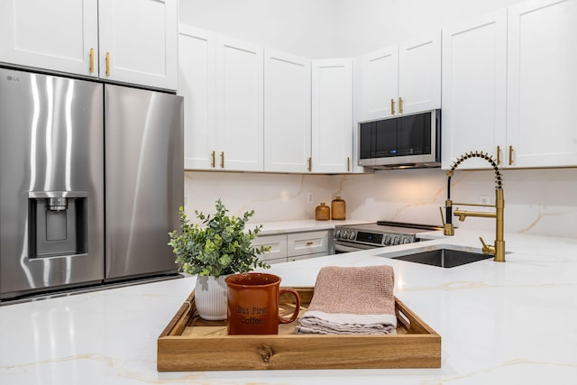 kitchen featuring white cabinets, light stone counters, sink, and stainless steel appliances