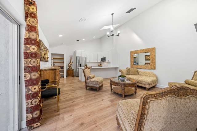 living room featuring high vaulted ceiling, a chandelier, and light hardwood / wood-style floors